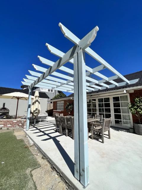 Close view of a white timber pergola post and beams against blue sky
