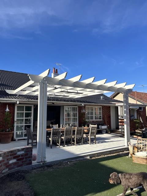 White-painted timber pergola over a rear courtyard dining area